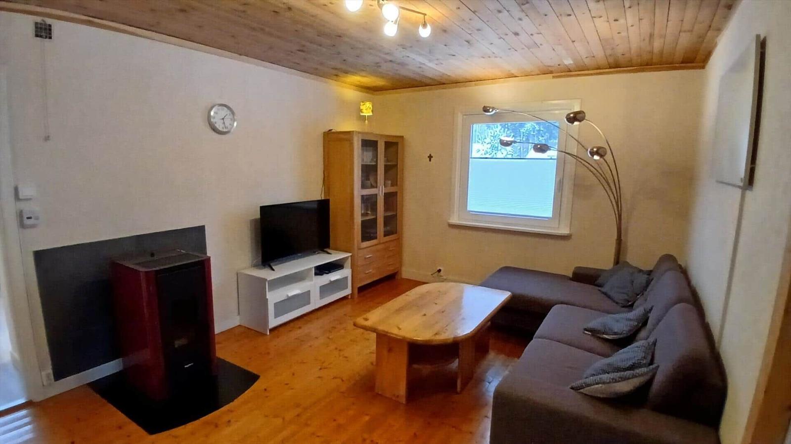 Wohnzimmer mit Sofa, Fernseher und Holztisch.