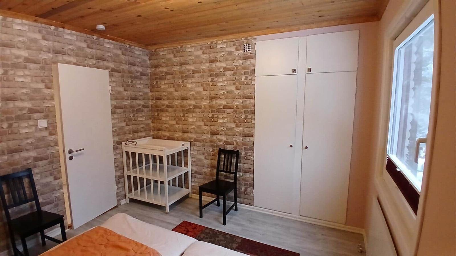 Schlafzimmer mit Holzdecke, Ziegelwand, Kleiderschrank und Babywanne.