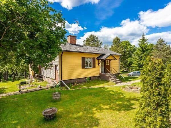 Gelbes Haus mit Garten und Terrasse unter blauem Himmel.