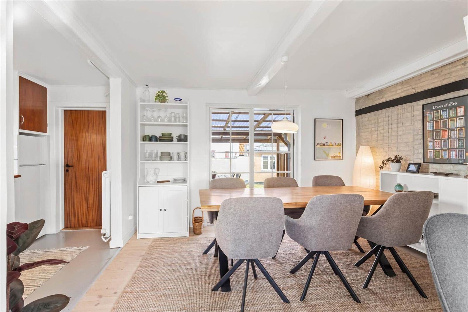 Dining room with wooden table, gray chairs, and glass door to garden