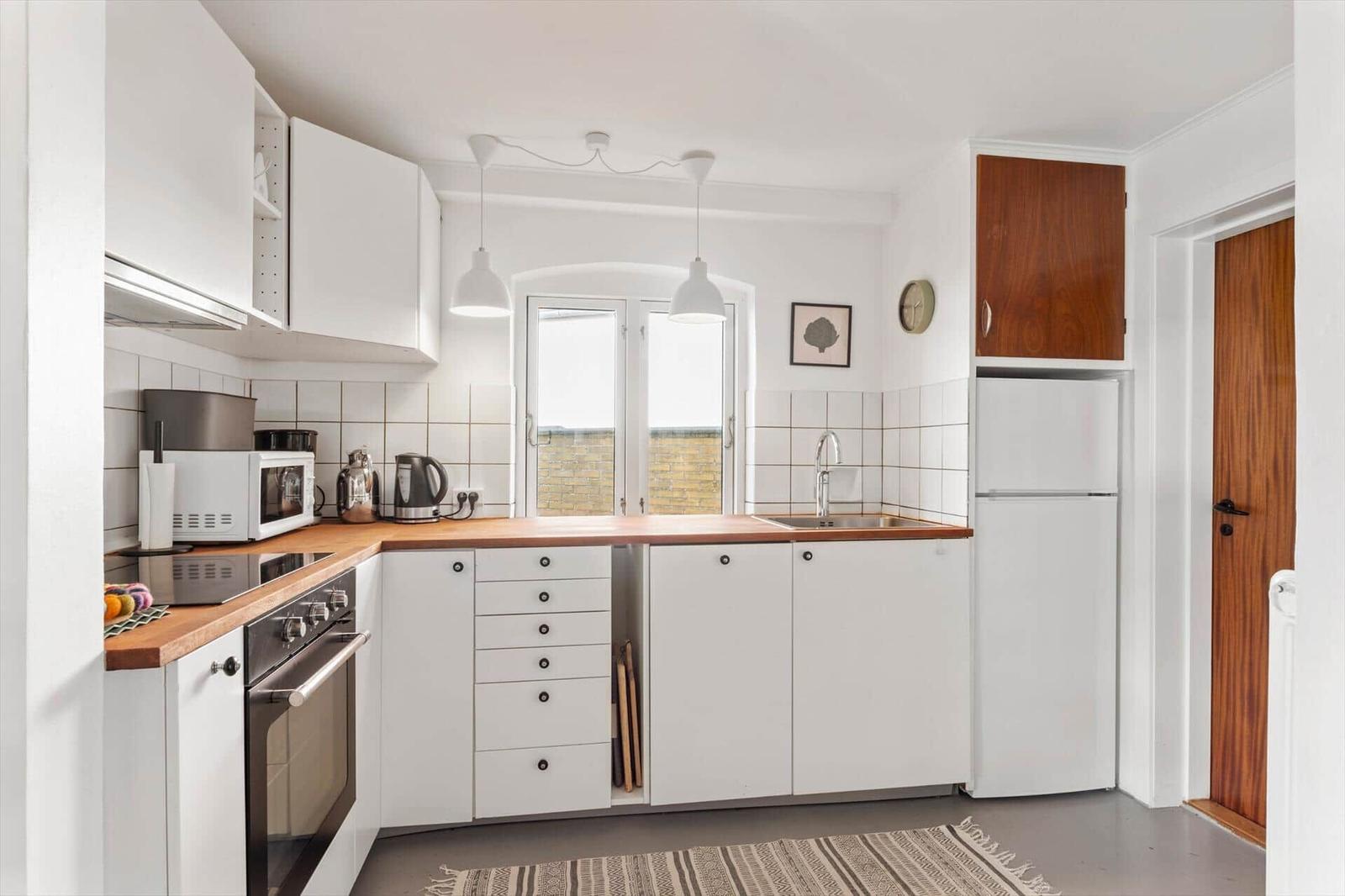Kitchen with white cabinets, wooden countertop, and window with view.