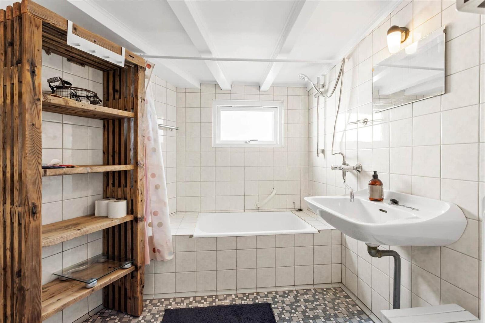 Bathroom with bathtub, sink, and wooden shelf.