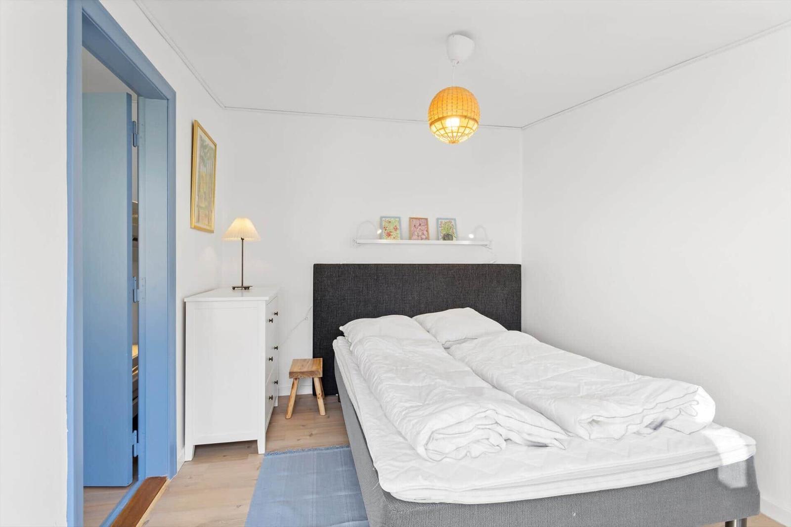 Bedroom with bed, nightstand, stool, and duvet. Door leads to a closet.