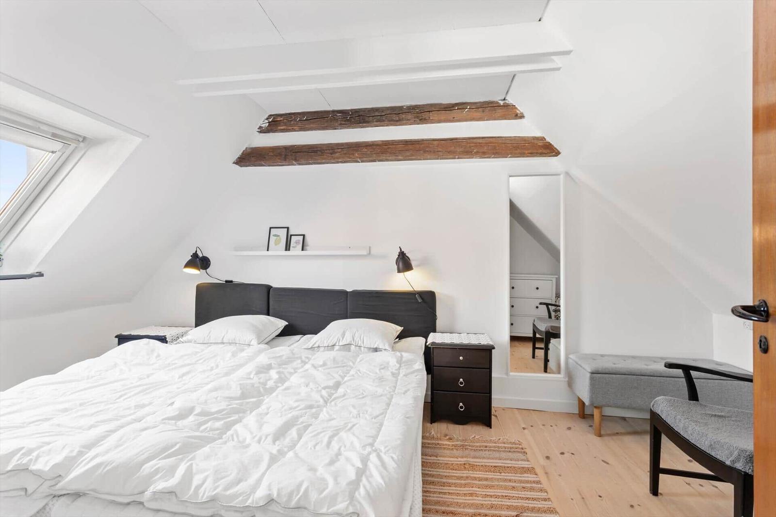 Bedroom with sloped ceiling, bed, nightstand, and window