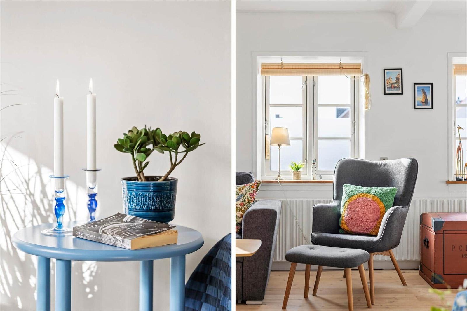 A room with a gray armchair, window, and small table with plant and candles.
