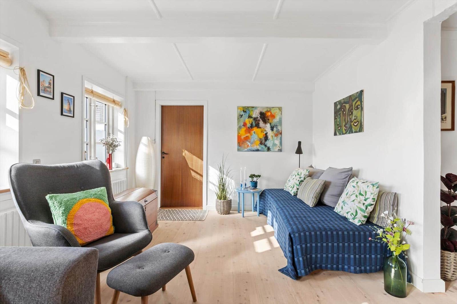 A room with a sofa, an armchair, and artwork on the walls.