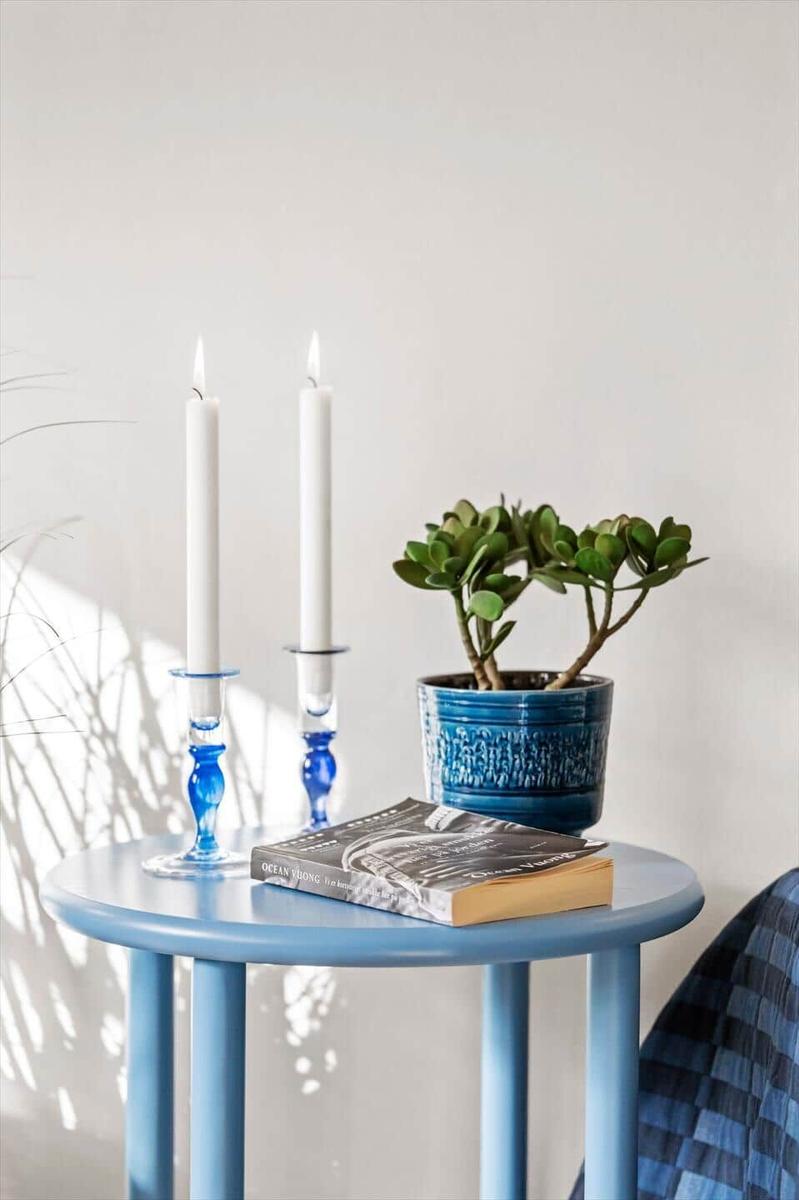 Blue table with candles, plant, and book.