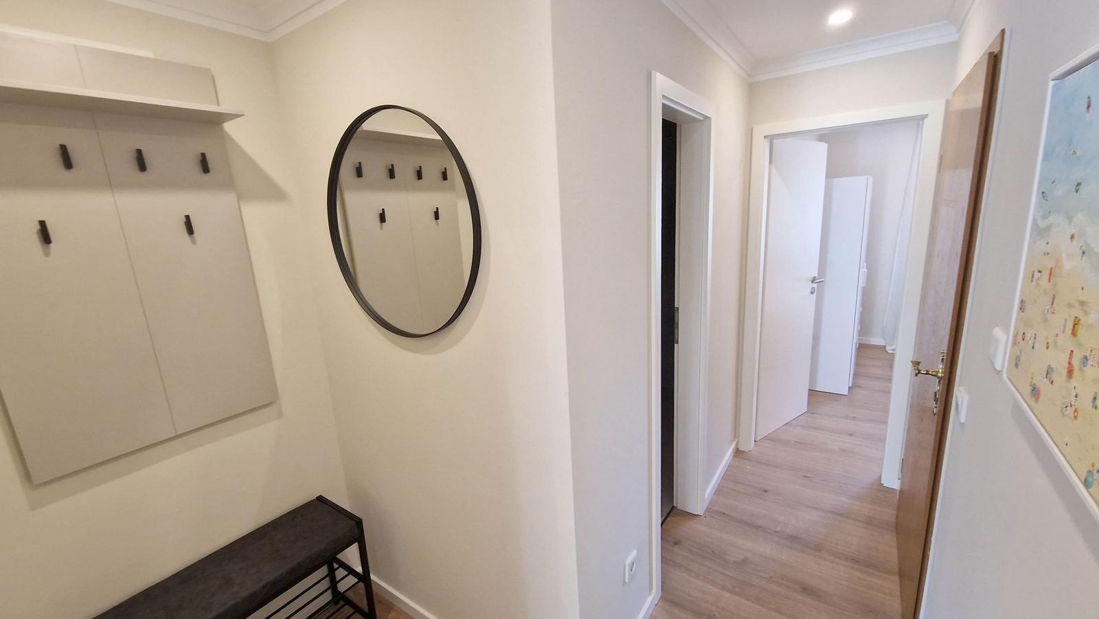 Eingangsbereich mit Garderobe, Spiegel und Flur zu weiteren Räumen.