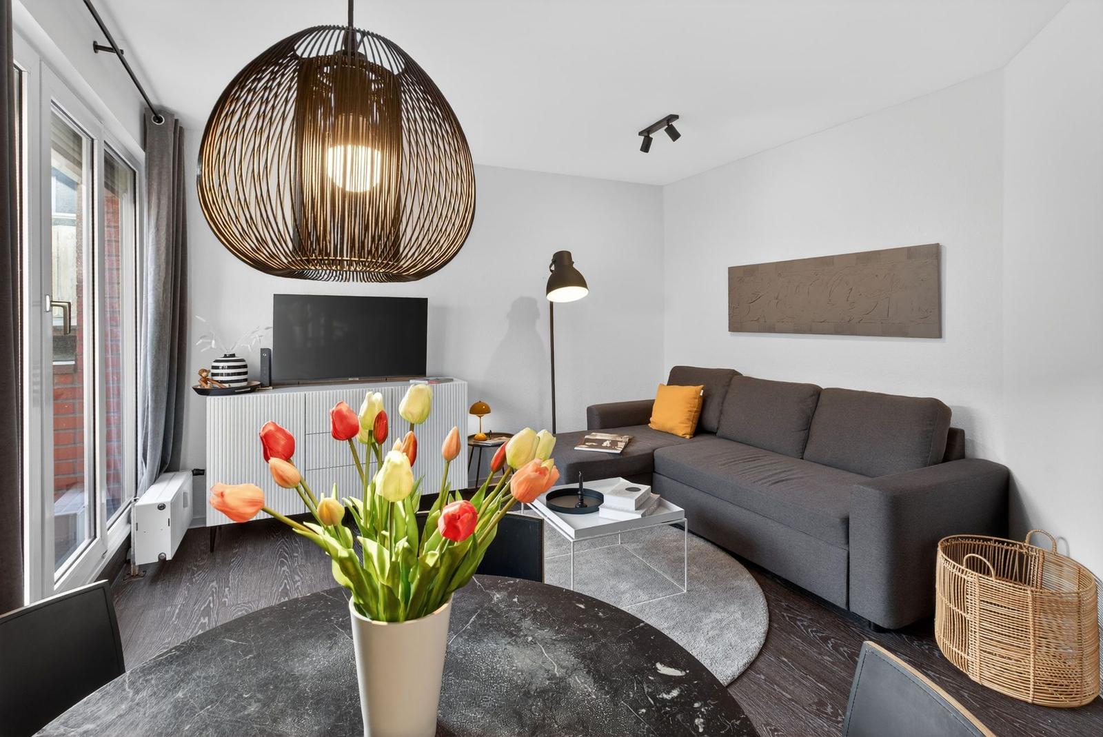 Wohnzimmer mit Sofa, Fernseher und Tulpen auf Tisch
