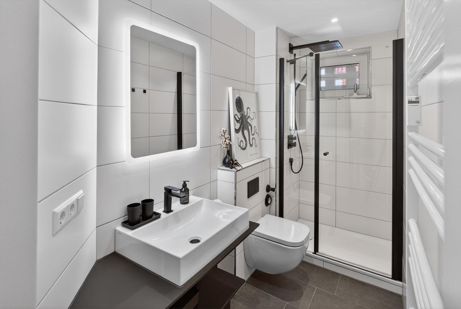 Badezimmer mit Dusche, Waschbecken und Toilette.
