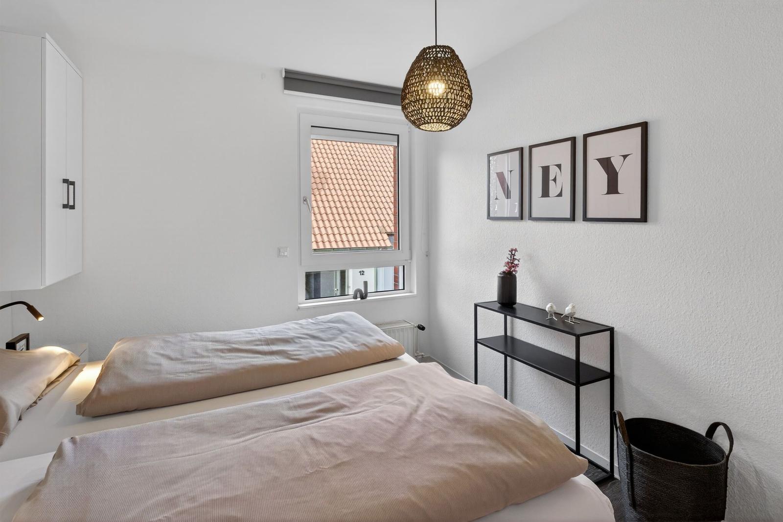 Schlafzimmer mit Bett, Fenster und Wanddekoration.
