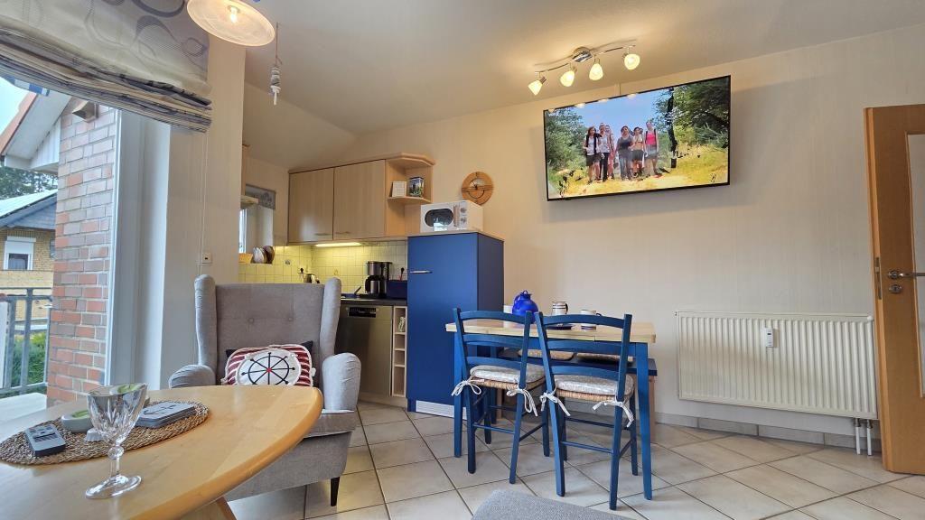 Wohnküche mit Esstisch, Sofa und Fernseher an der Wand.