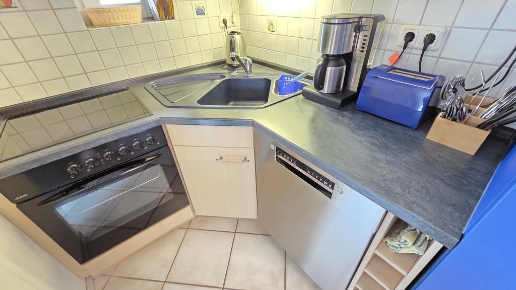 Küche mit Spüle, Kochfeld, Waschmaschine und Kaffeemaschine.