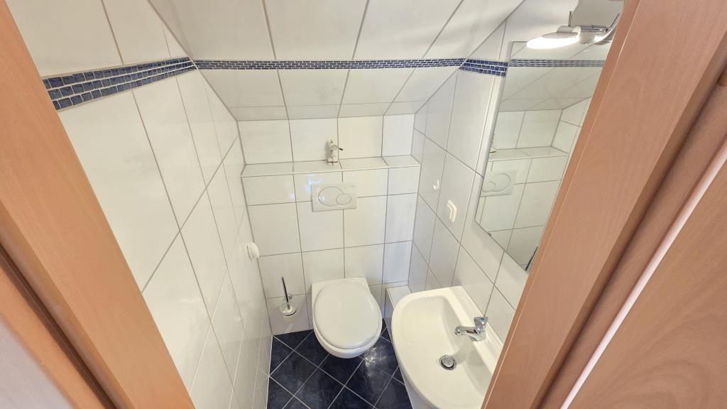 Badezimmer mit Toilette, Waschbecken und Spiegel.