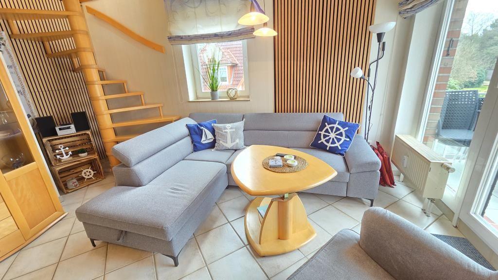 Wohnzimmer mit grauem Sofa, Holztisch und Treppe zur Galerie.
