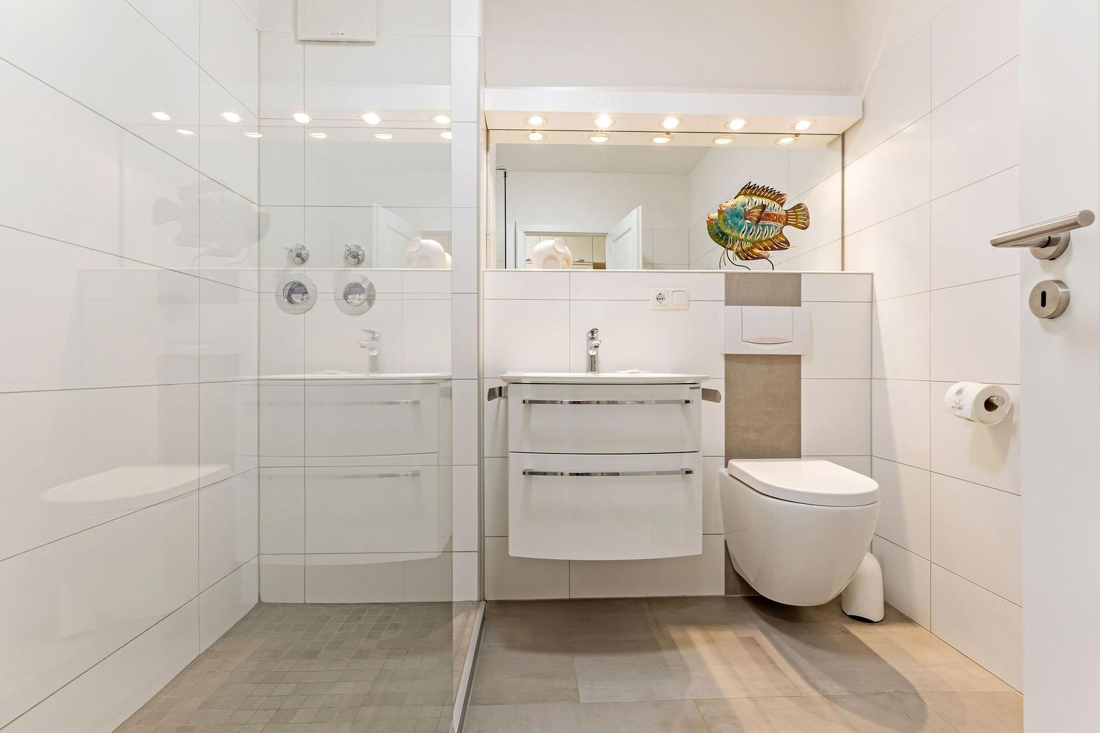 Badezimmer mit Dusche, Waschbecken und Toilette. Wandfliesen und moderne Einrichtung.