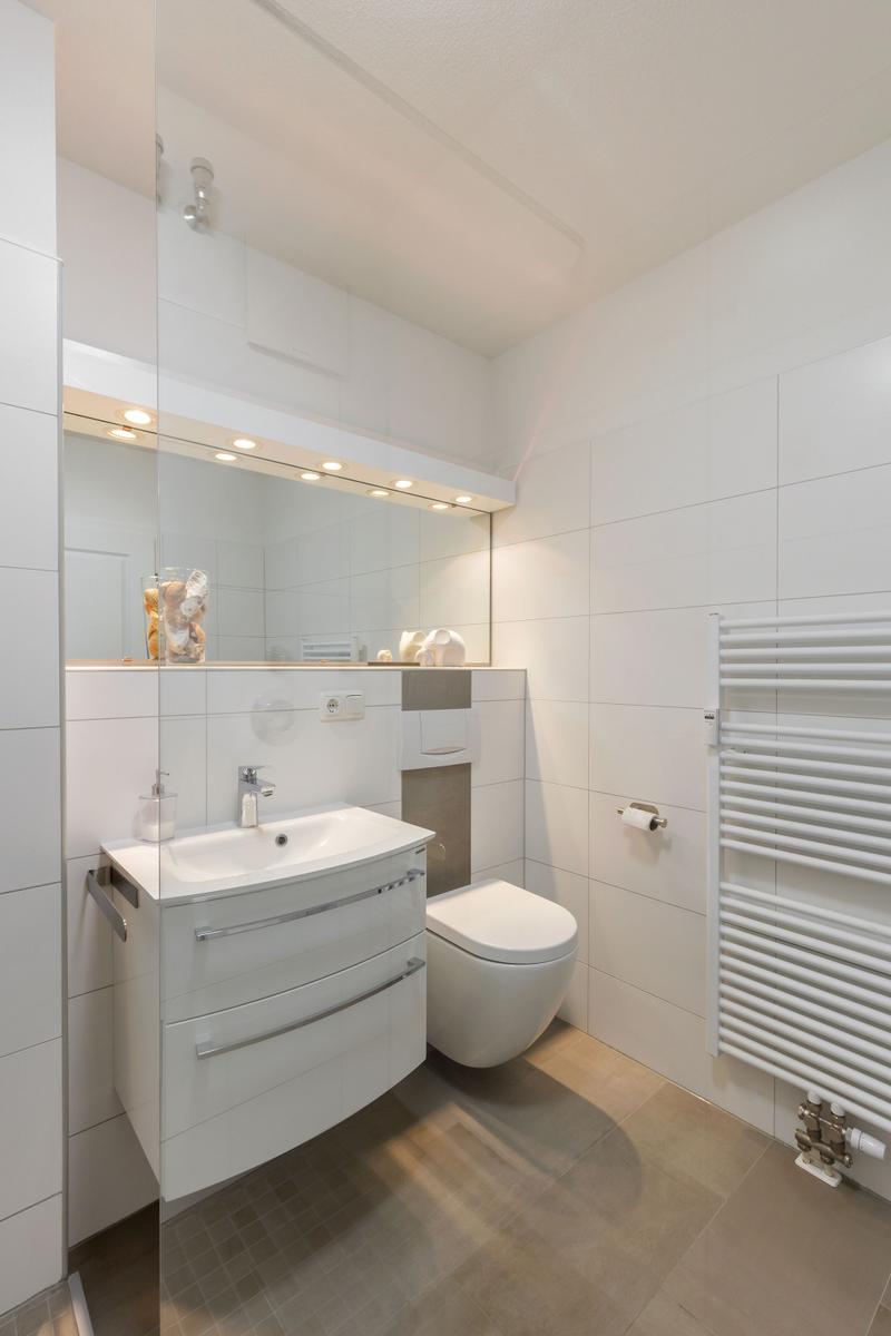 Badezimmer mit Waschbecken, Spiegel und Toilette
