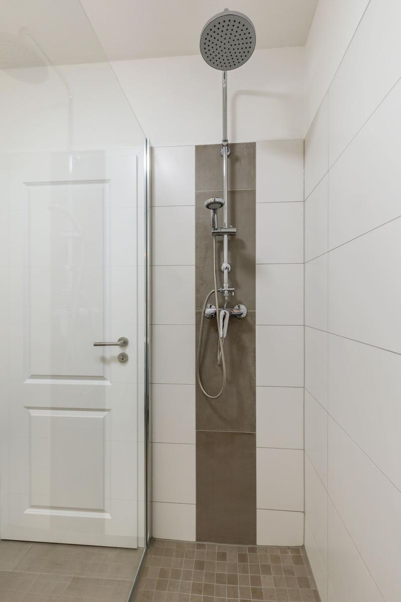 Dusche mit Duschbrause und Handbrause an Wand