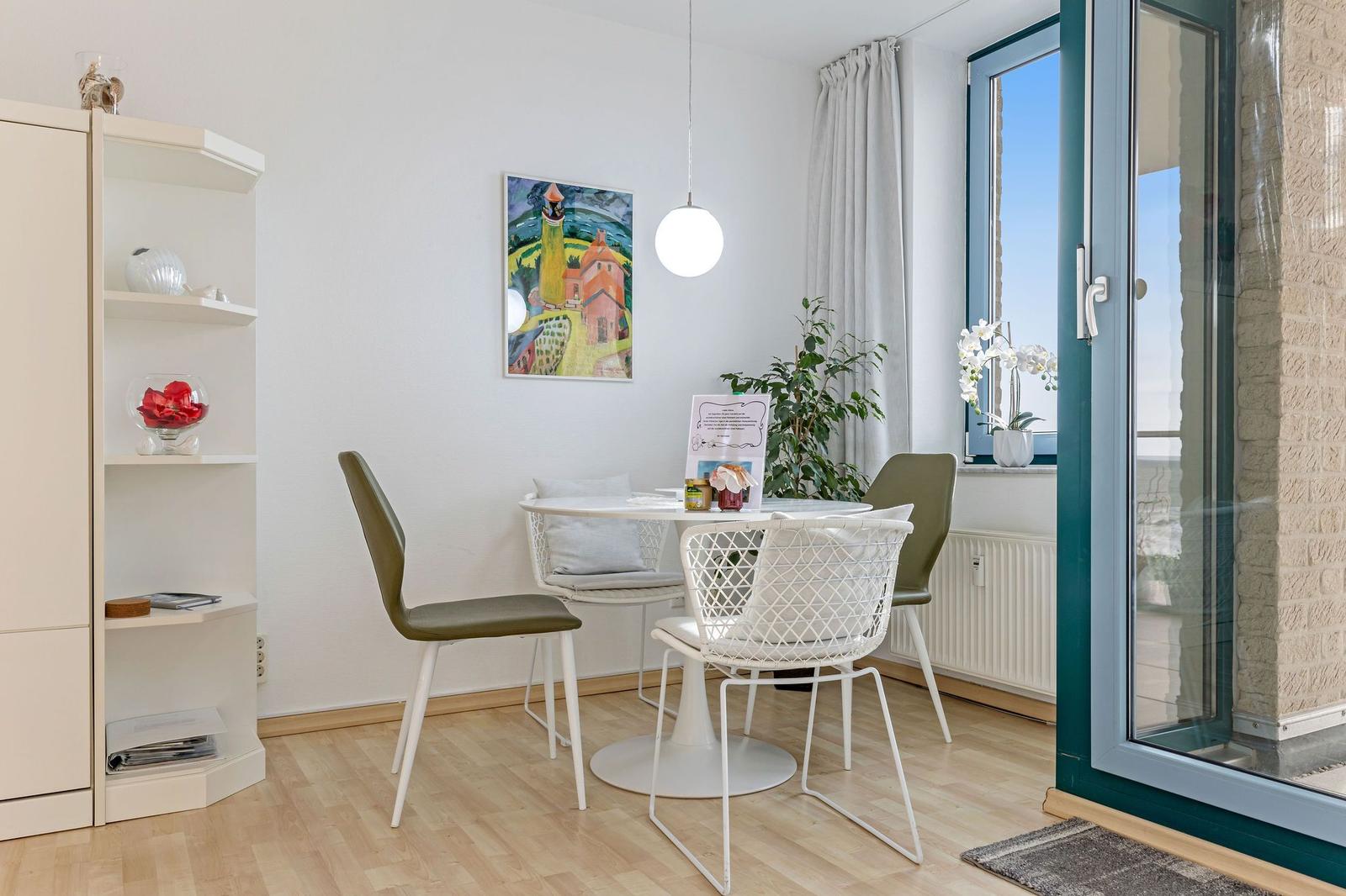 Esszimmer mit Tisch, Stühlen und Blick auf Balkon.