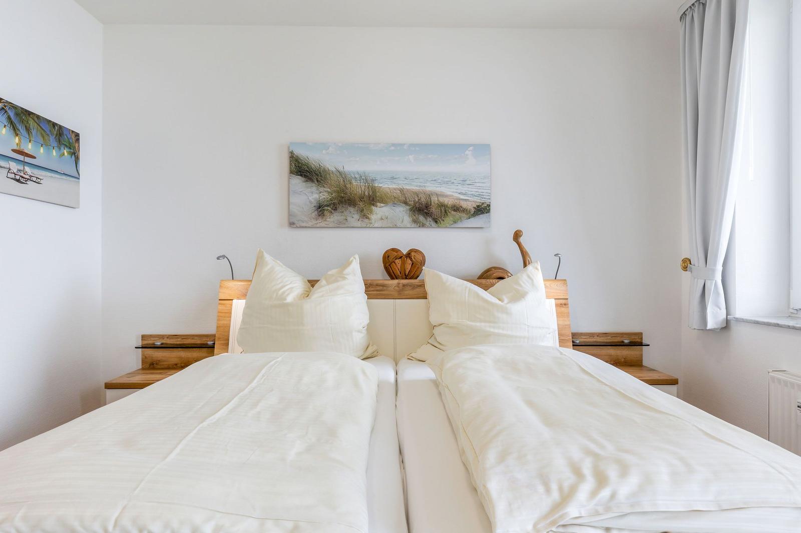 Zimmer mit Doppelbett, Holzkopfteil und Wandbildern