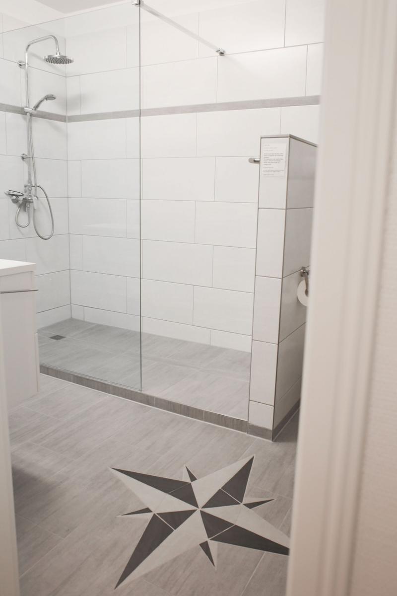 Bad mit Dusche, Toilette und Sternmusterbodenfliesen.