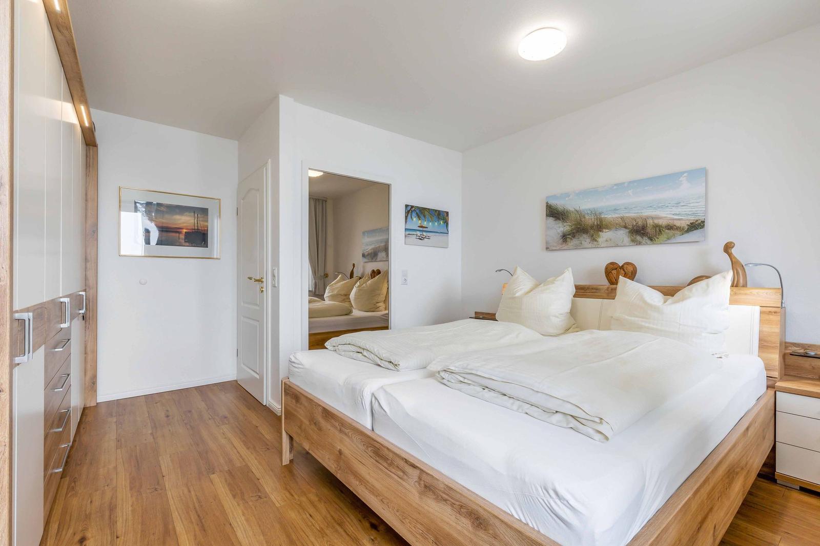 Schlafzimmer mit Doppelbett, Holzboden und Wandbildern