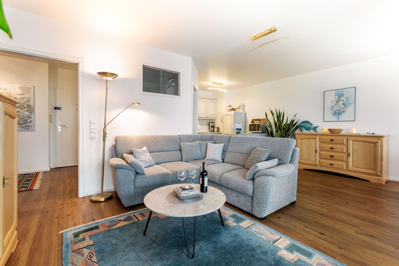 Wohnzimmer mit grauem Sofa, runden Tisch und Holzboden.