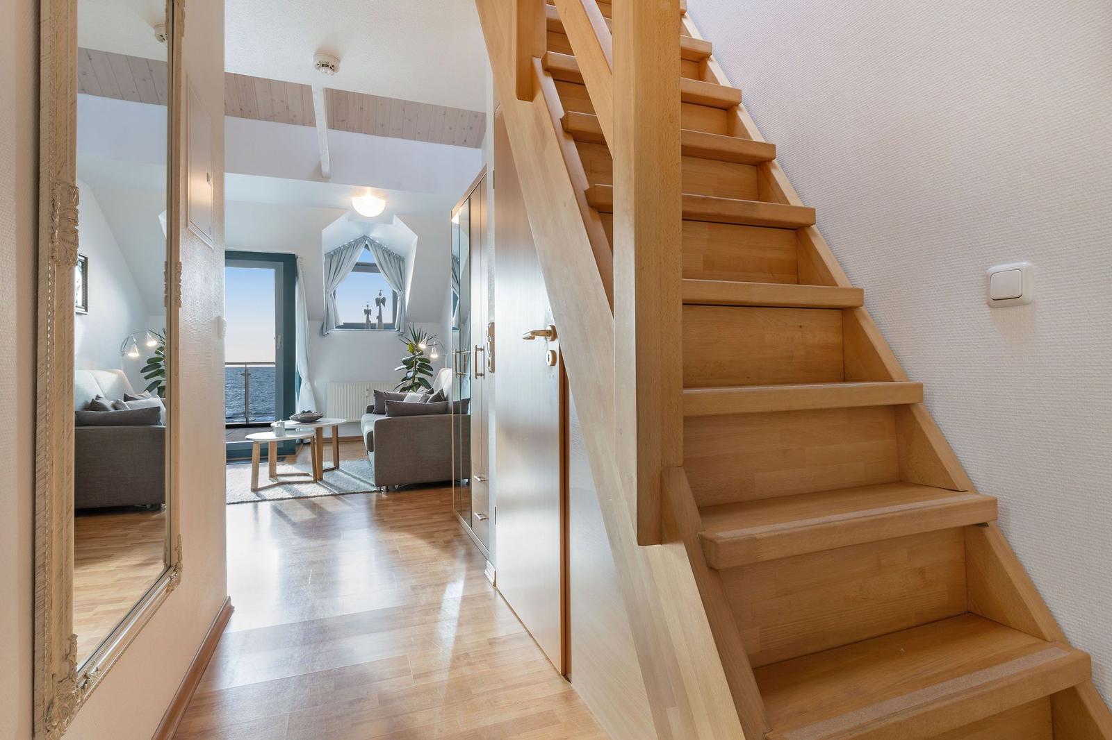 Holztreppe führt zu einer Wohnung mit Wohnbereich und Meerblick.