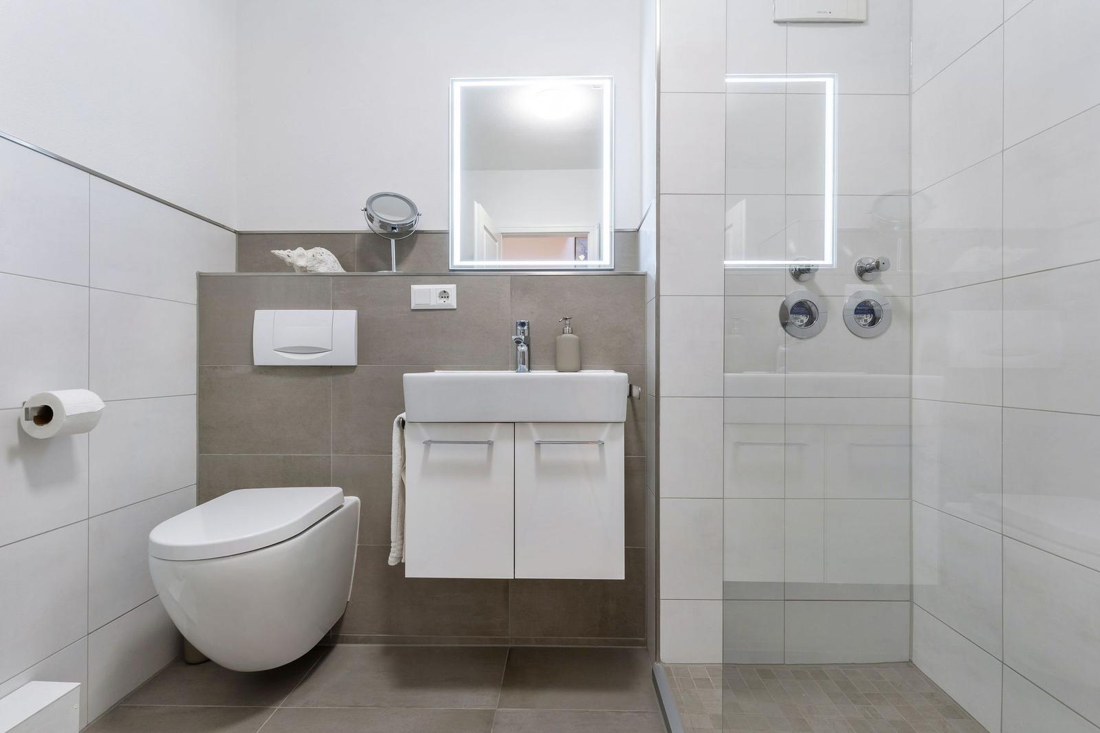 Badezimmer mit Dusche, Waschbecken und Toilette.