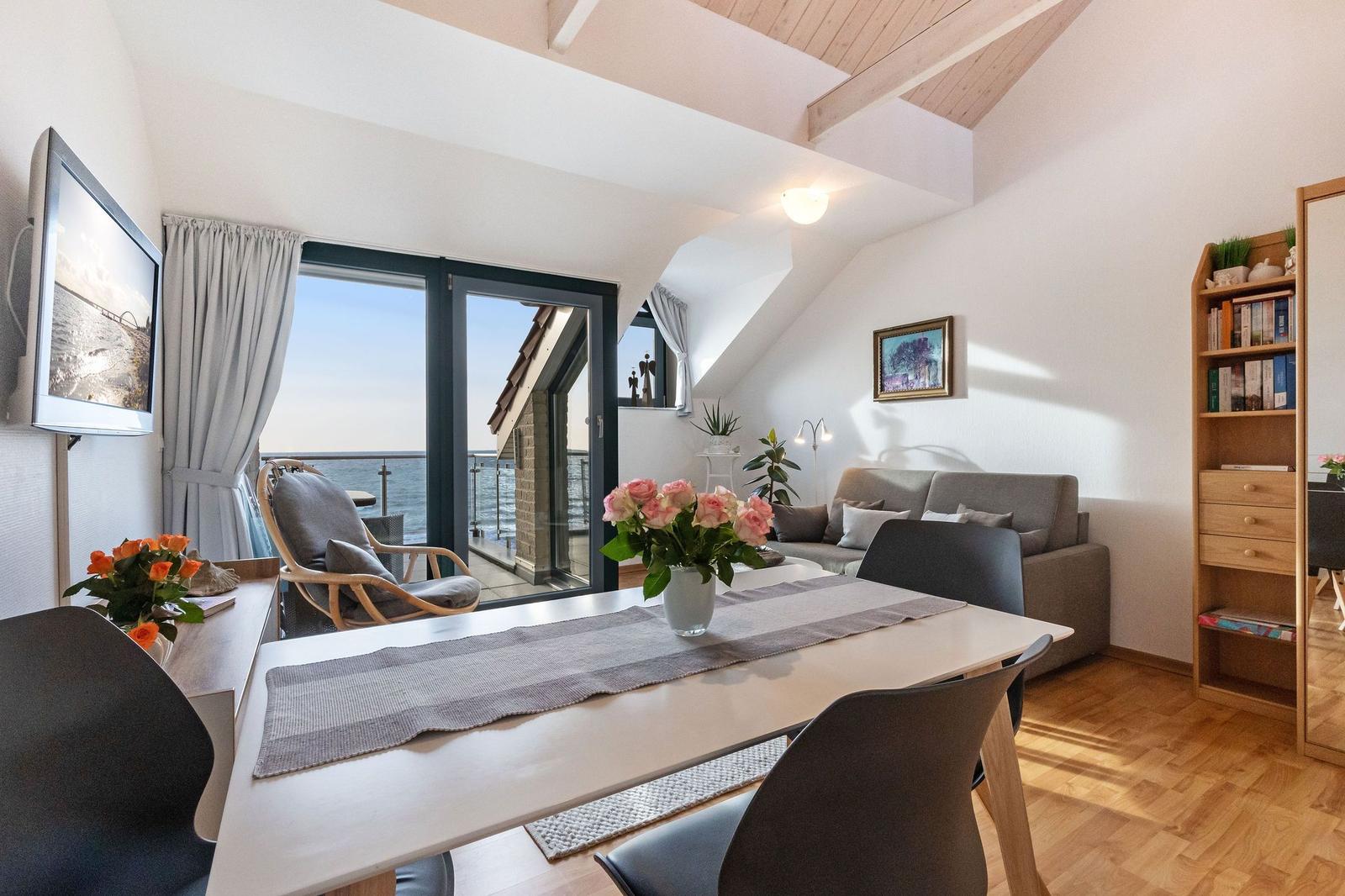 Wohnbereich mit Esstisch, Sofa und Balkontür zum Meer.