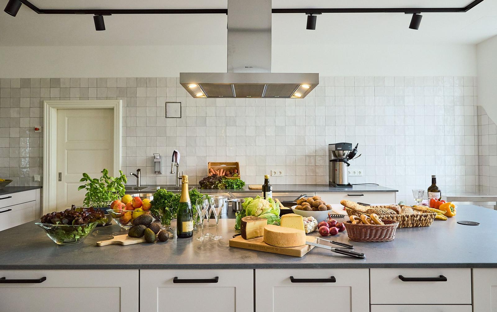 Moderne Küche mit Arbeitsplatte, Obst, Gemüse und Käse. Hintergrund: weiße Fliesen und Küchenspüle.