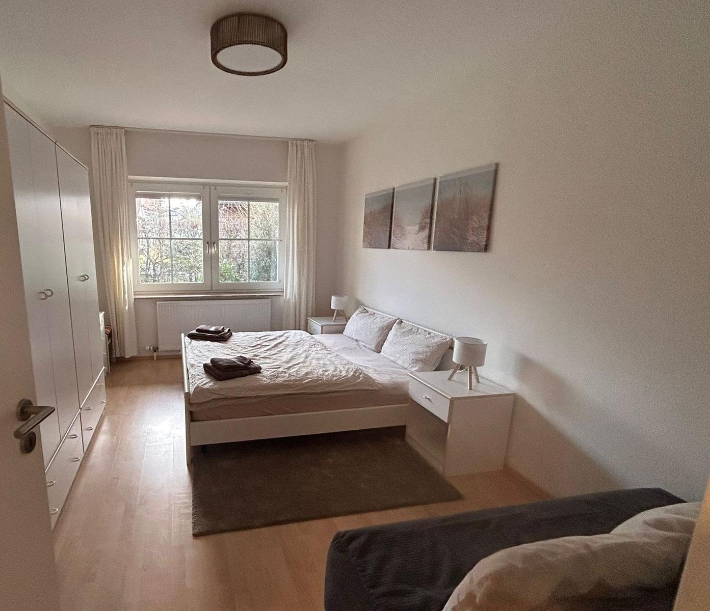 Schlafzimmer mit Bett, Nachttischen und Fenster.