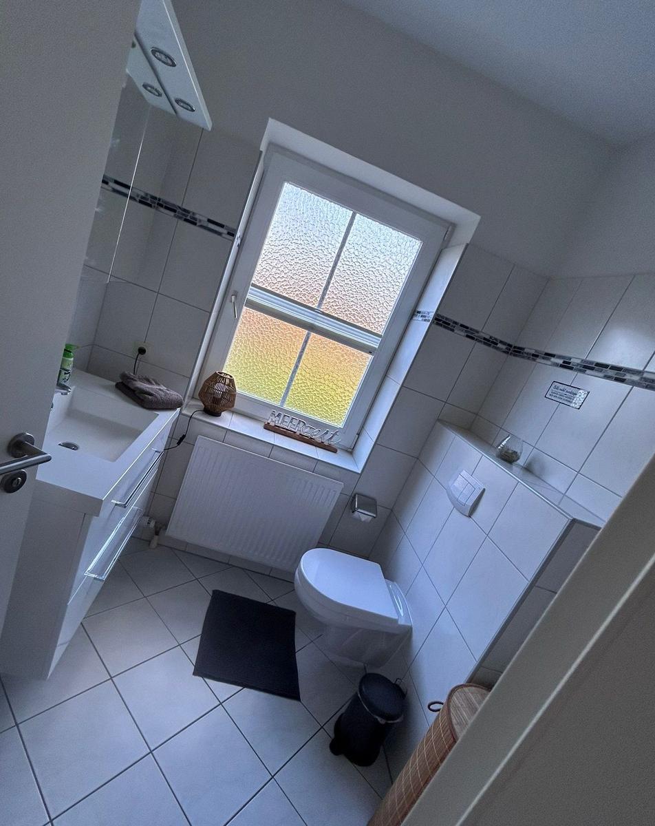 Badezimmer mit Toilette, Waschbecken und Fenster mit getöntem Glas.