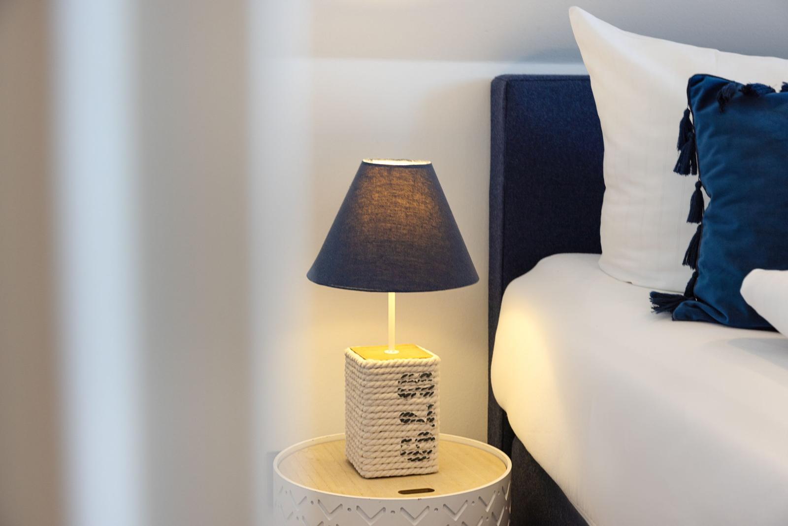 Nachttisch mit Lampe neben Bett mit Kissen