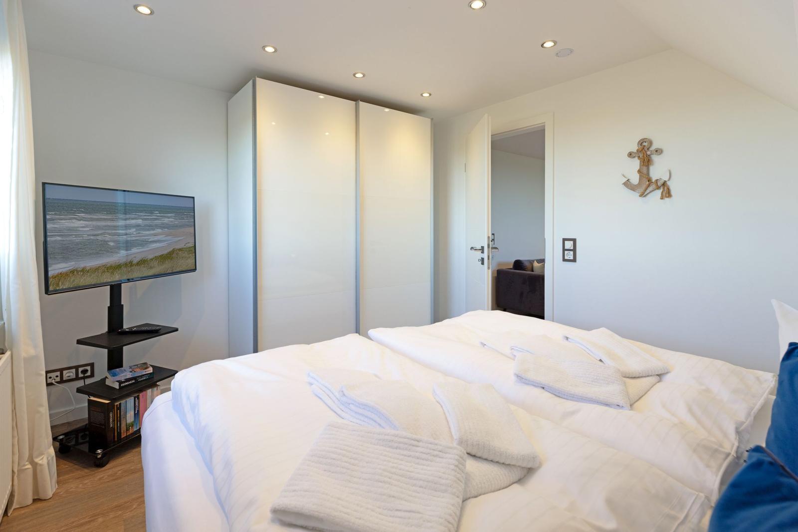 Schlafzimmer mit Bett, Kleiderschrank und Fernseher