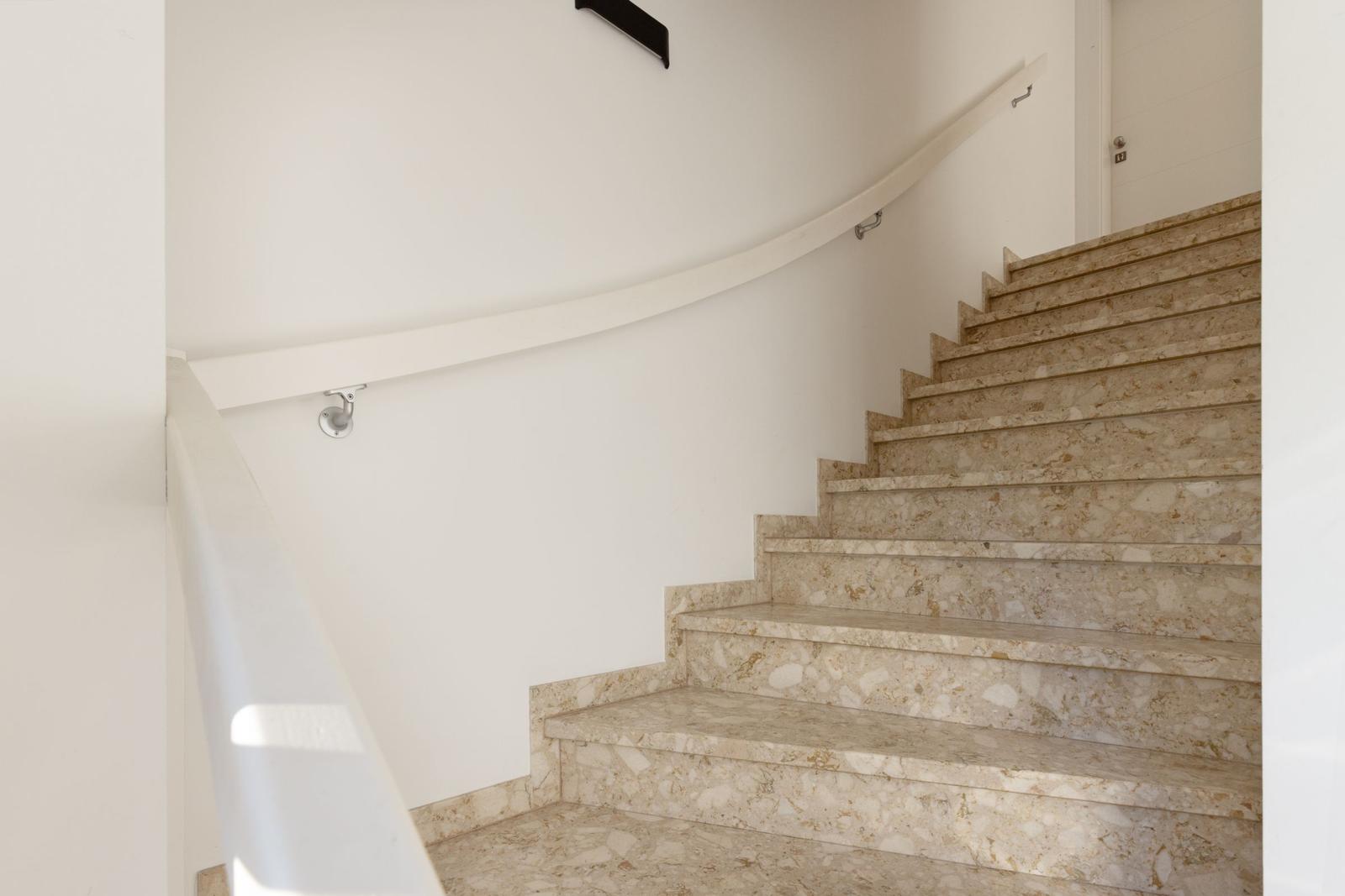 Treppe mit Marmorstufen und weißer Geländerwand.
