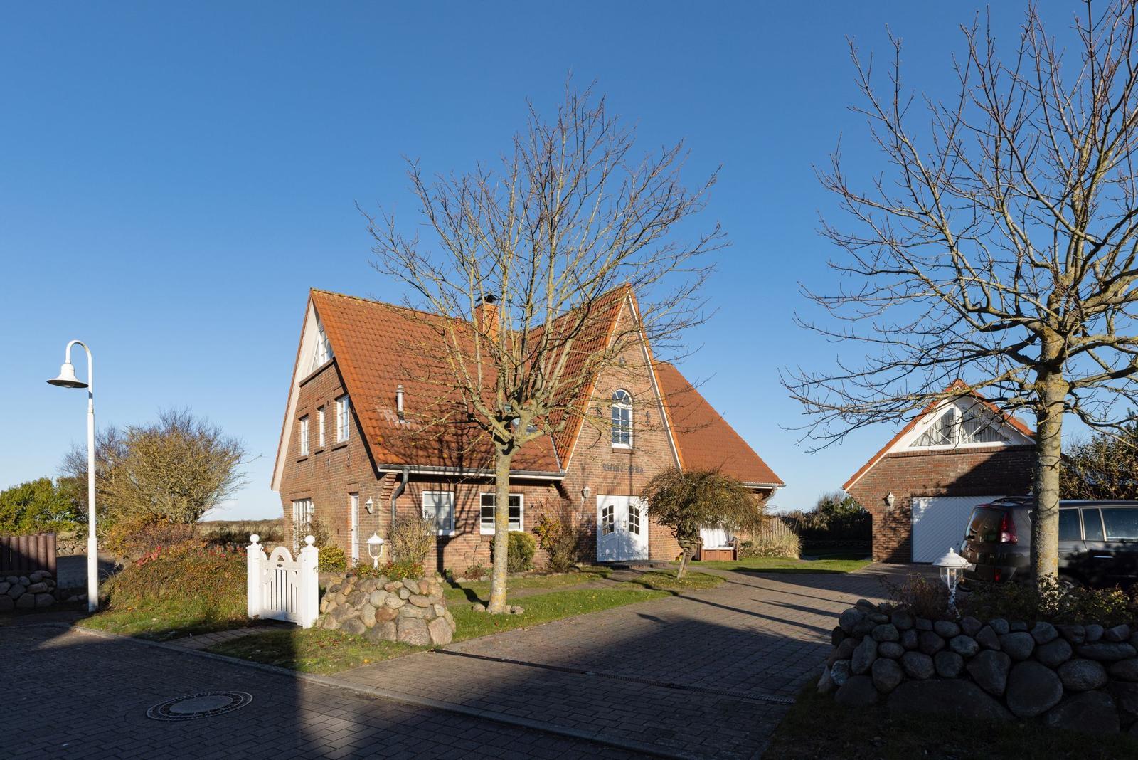 Haus mit rotem Dach, weißer Tür und Garten