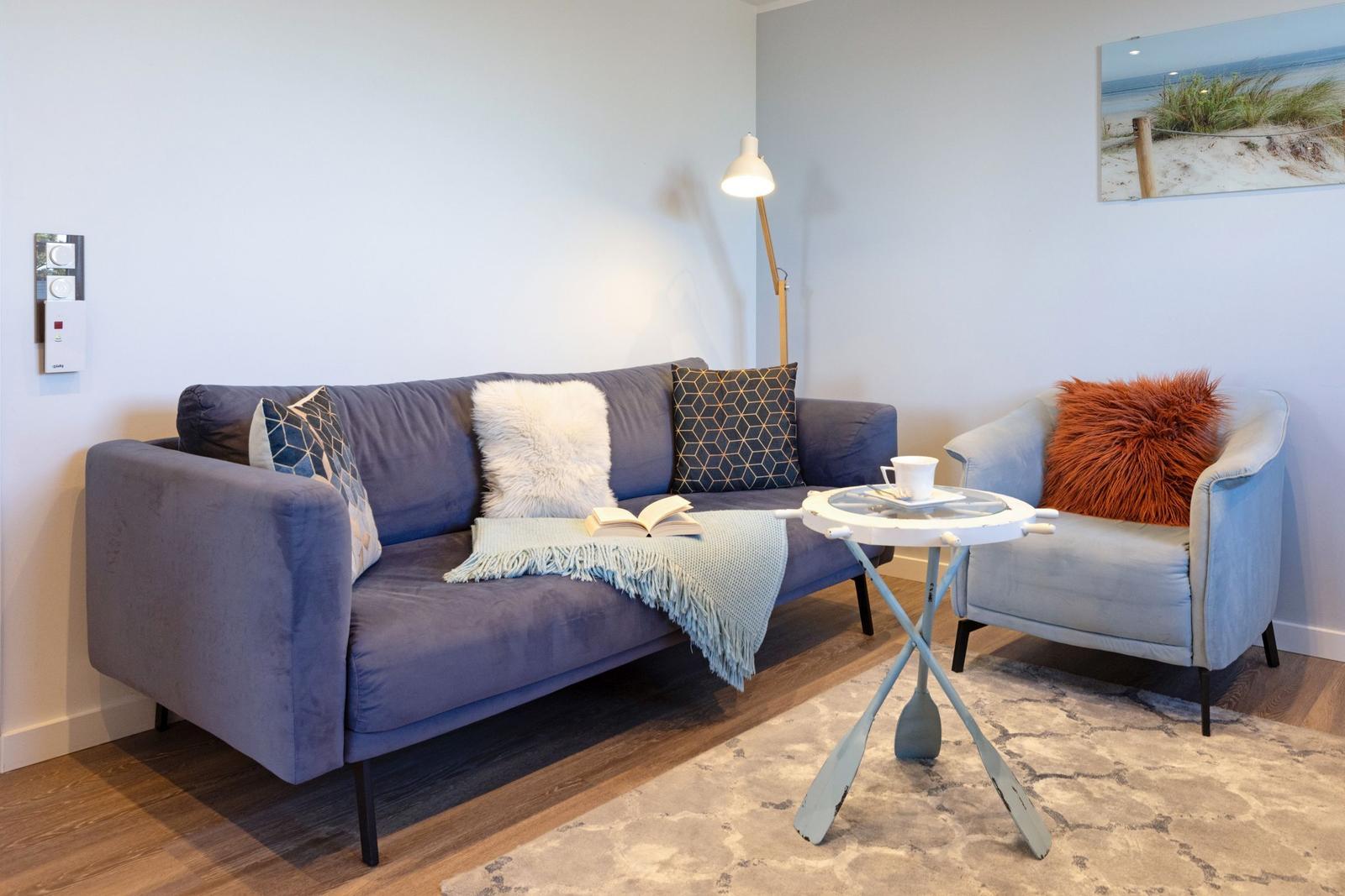 Ein Wohnzimmer mit Sofa, Sessel, Tisch und Wandbild.