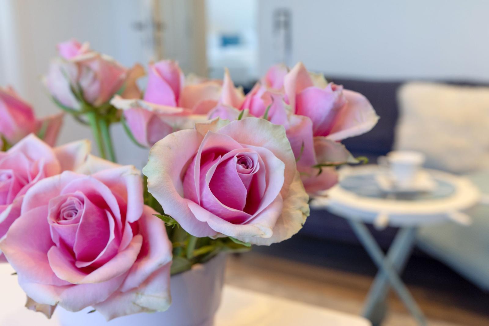 Ein Strauß rosa Rosen steht auf einem Tisch vor einem Sofa.