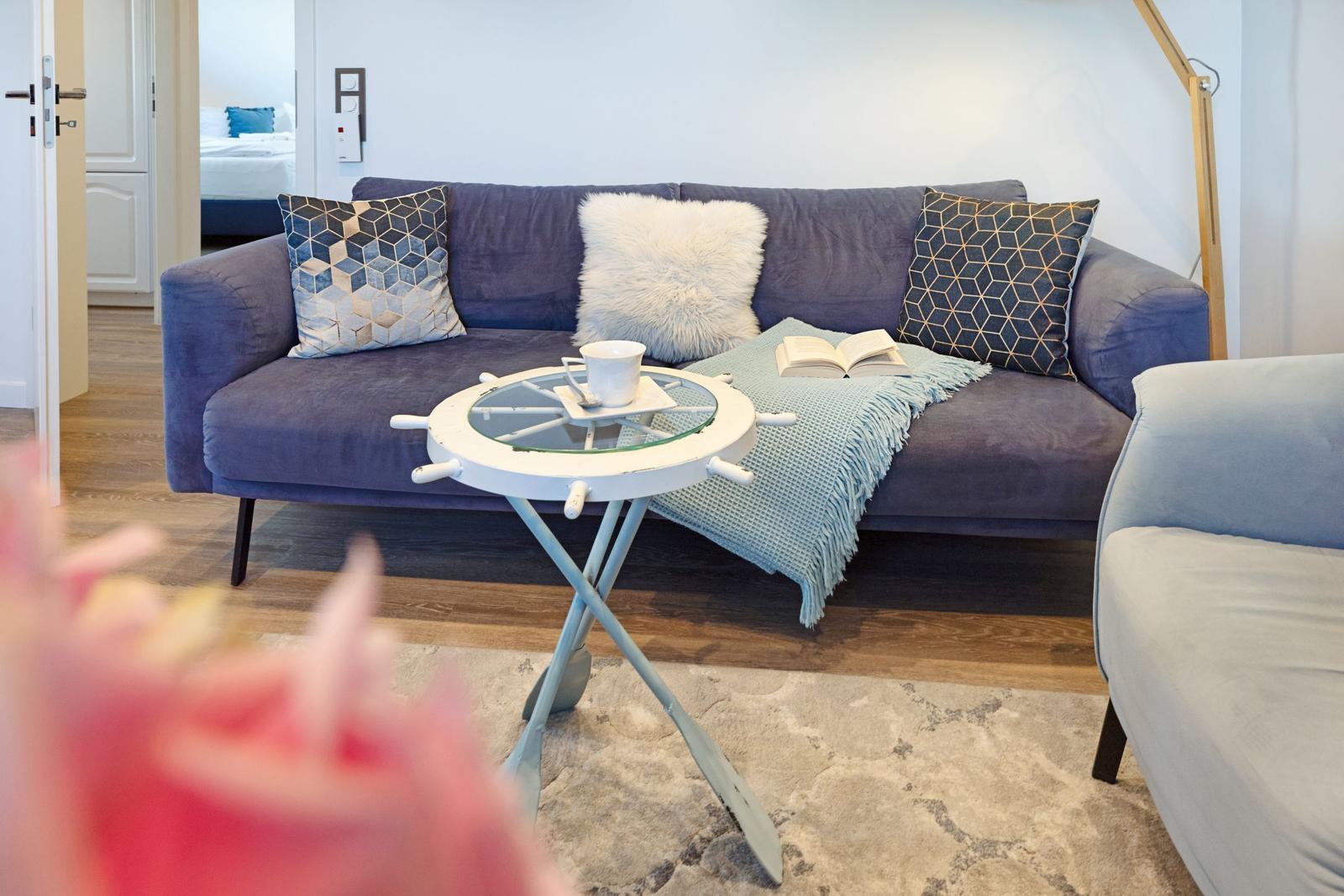 Ein Wohnzimmer mit blauem Sofa, Kissen und einem Tisch mit Ruder.