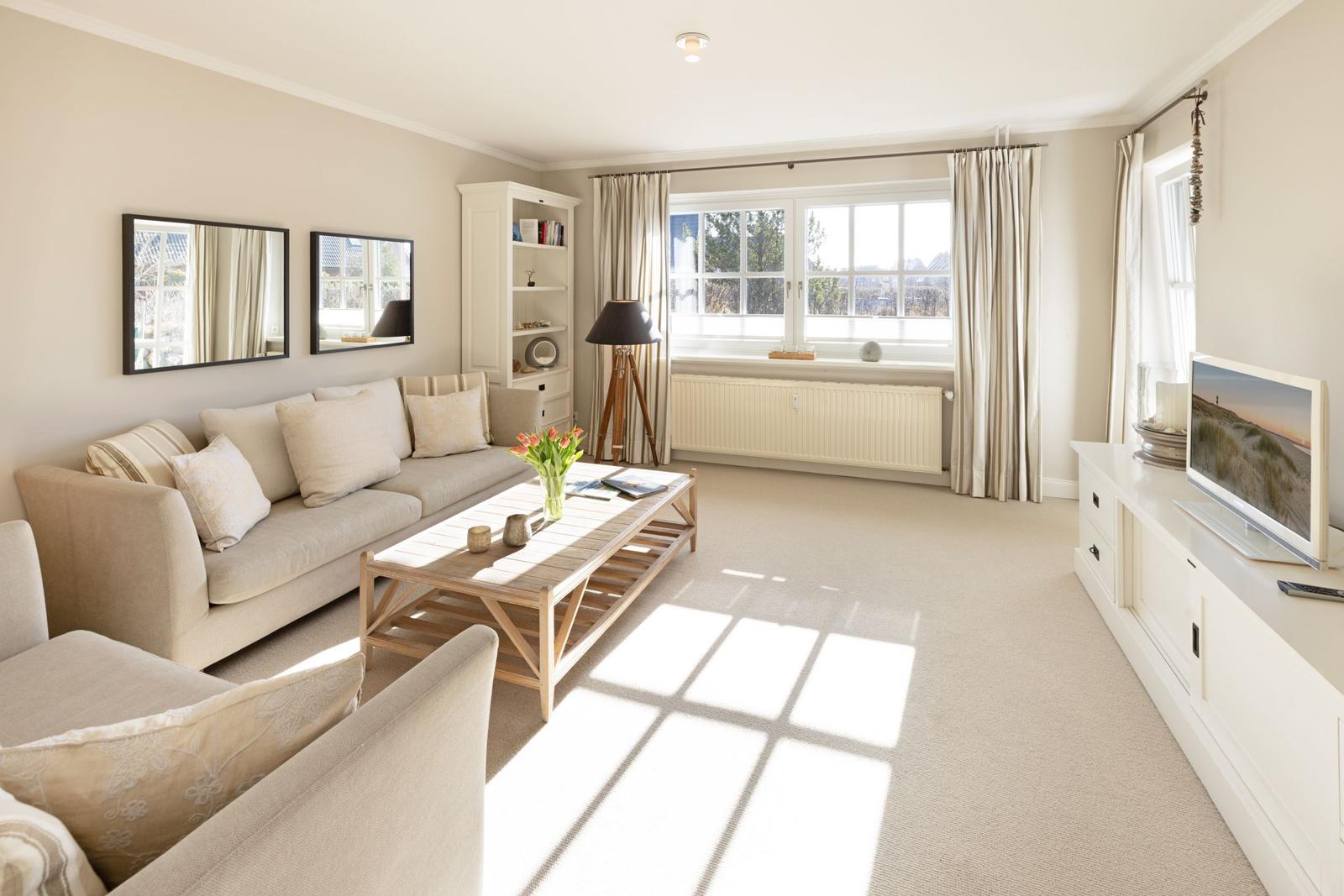 Wohnzimmer mit Sofa, Couchtisch und Fenster. Fernseher auf weißen Schrank.