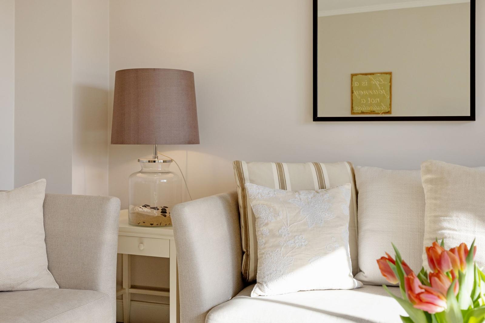 Sofa mit Kissen, Tischlampe und Blumen im Wohnbereich.