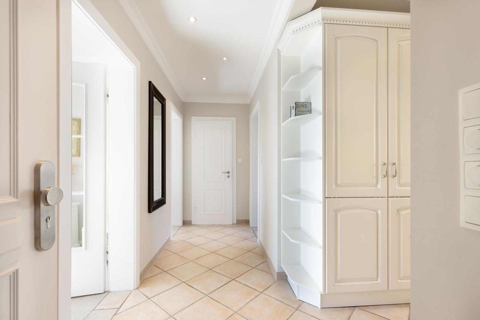Flur mit weißen Türen, Schrank und Spiegel an der Wand.