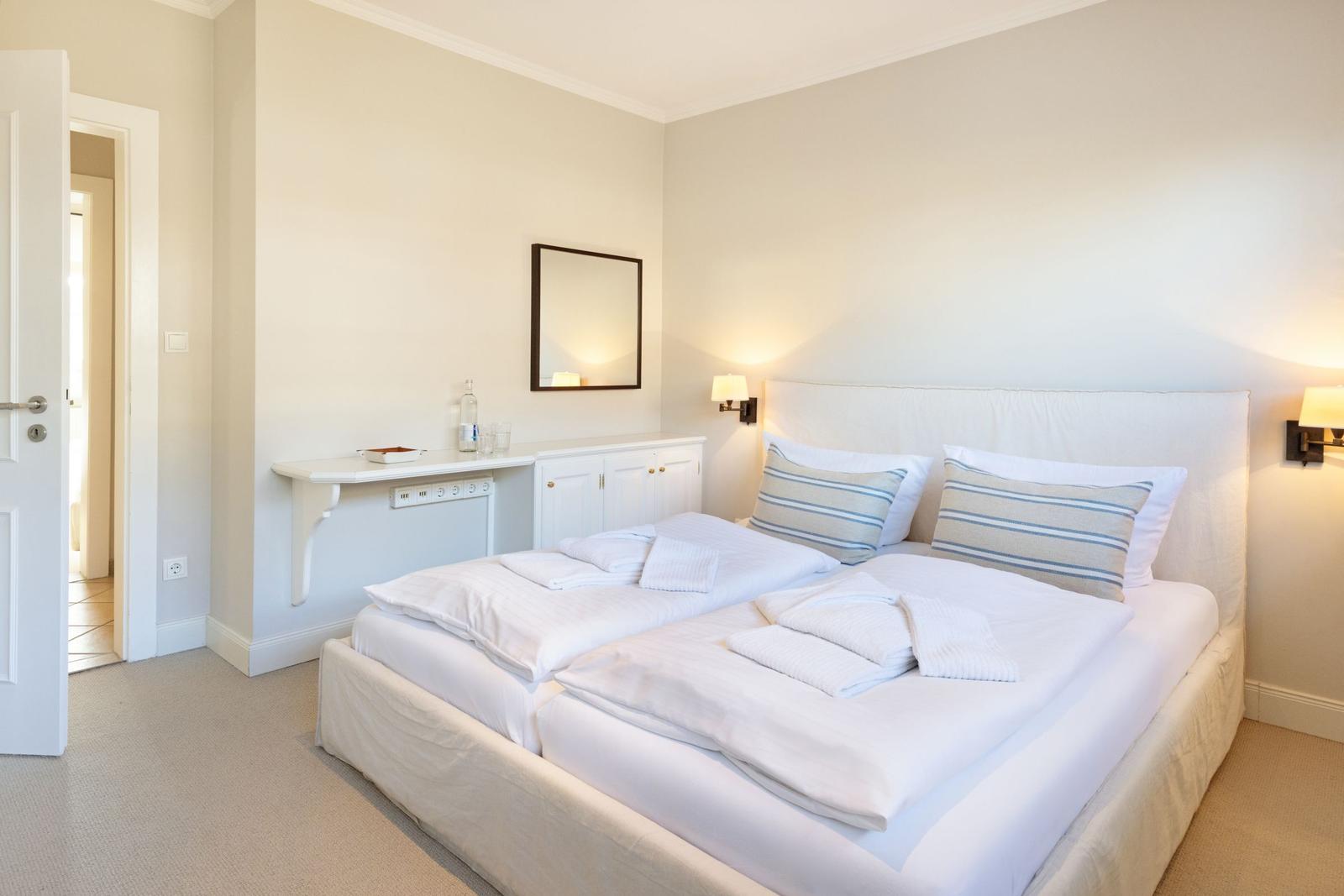 Schlafzimmer mit Doppelbett, Nachttischen und Spiegel an der Wand.