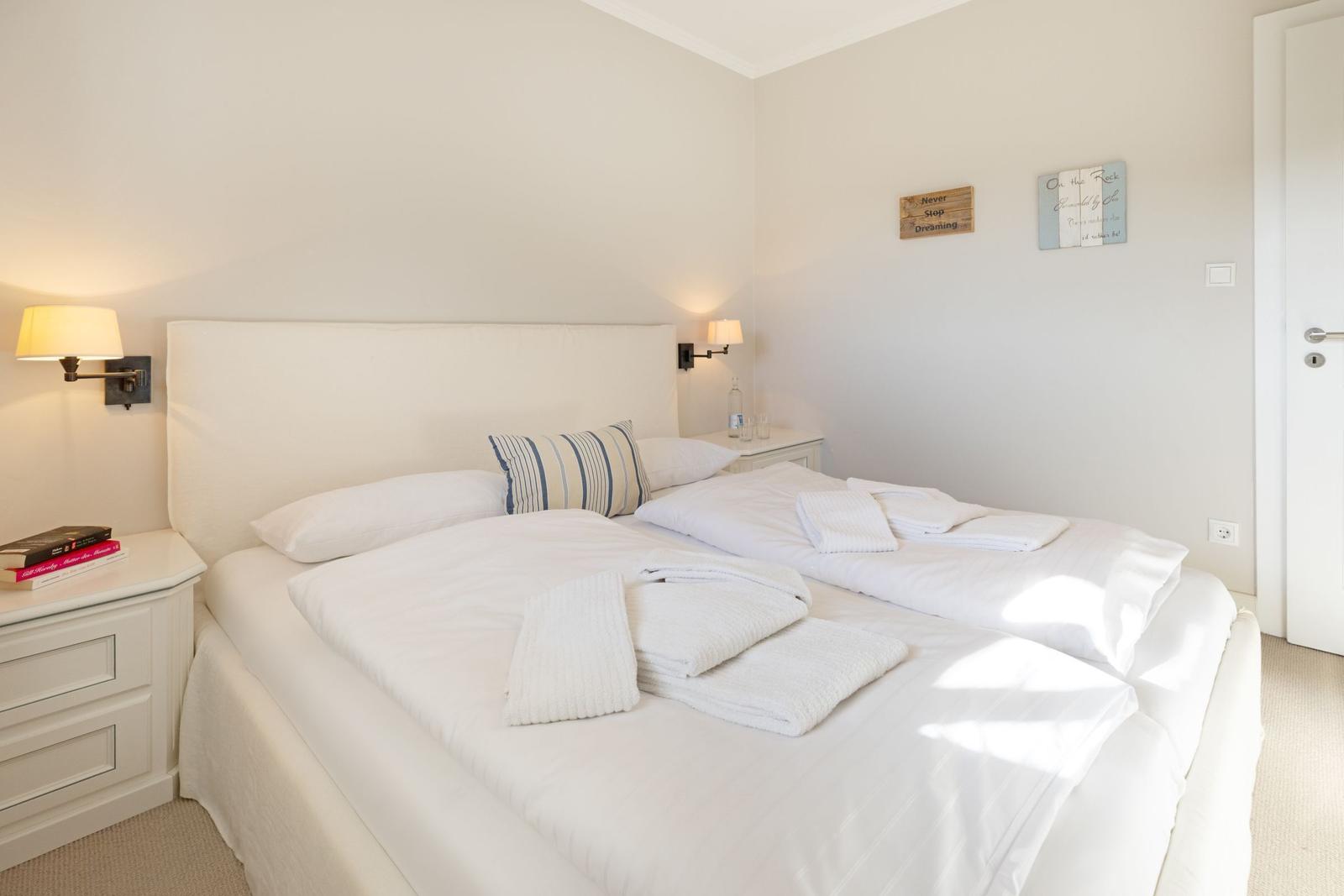Schlafzimmer mit Doppelbett, Nachttisch und Wandbeleuchtung.