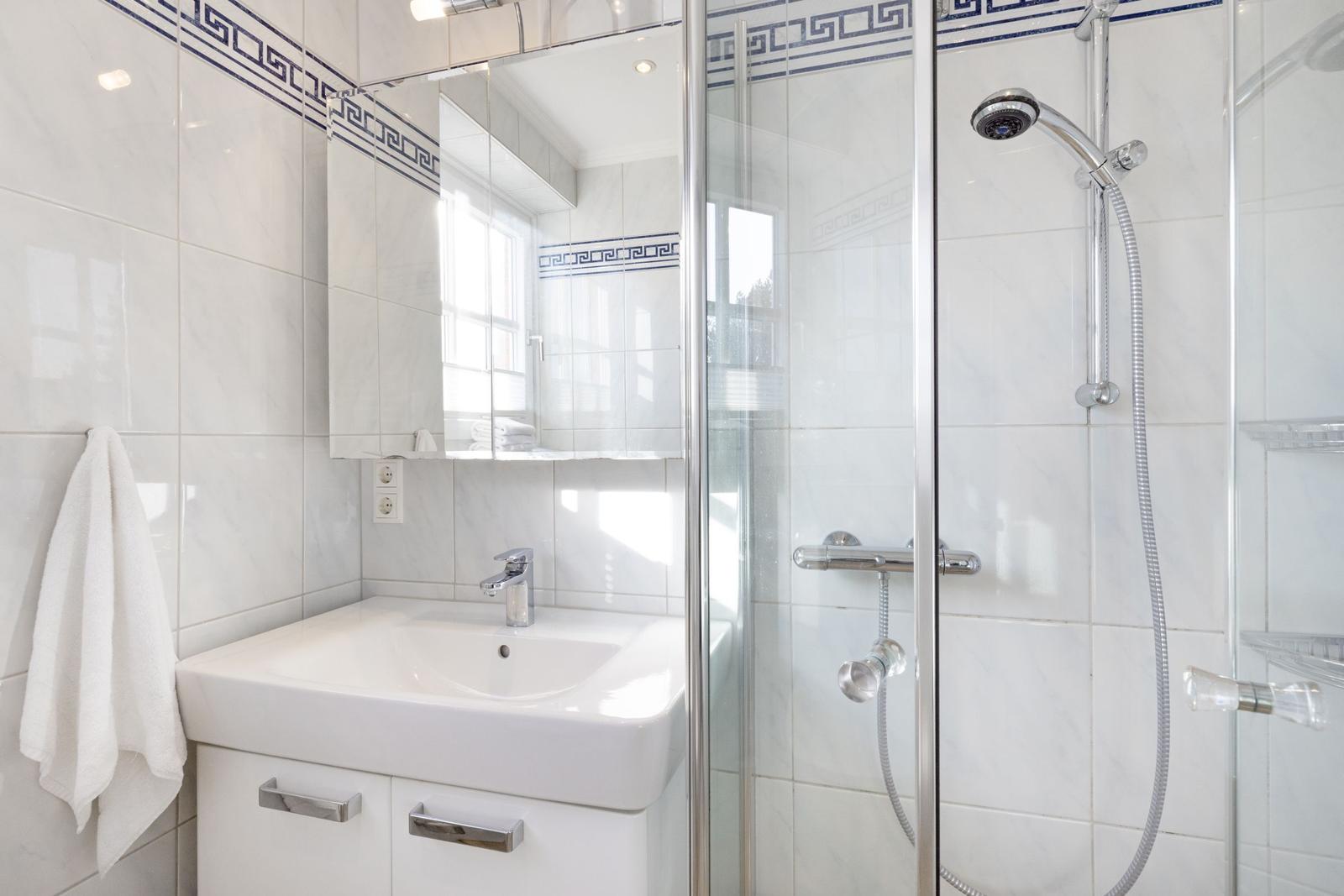 Badezimmer mit Dusche, Waschbecken und Spiegel