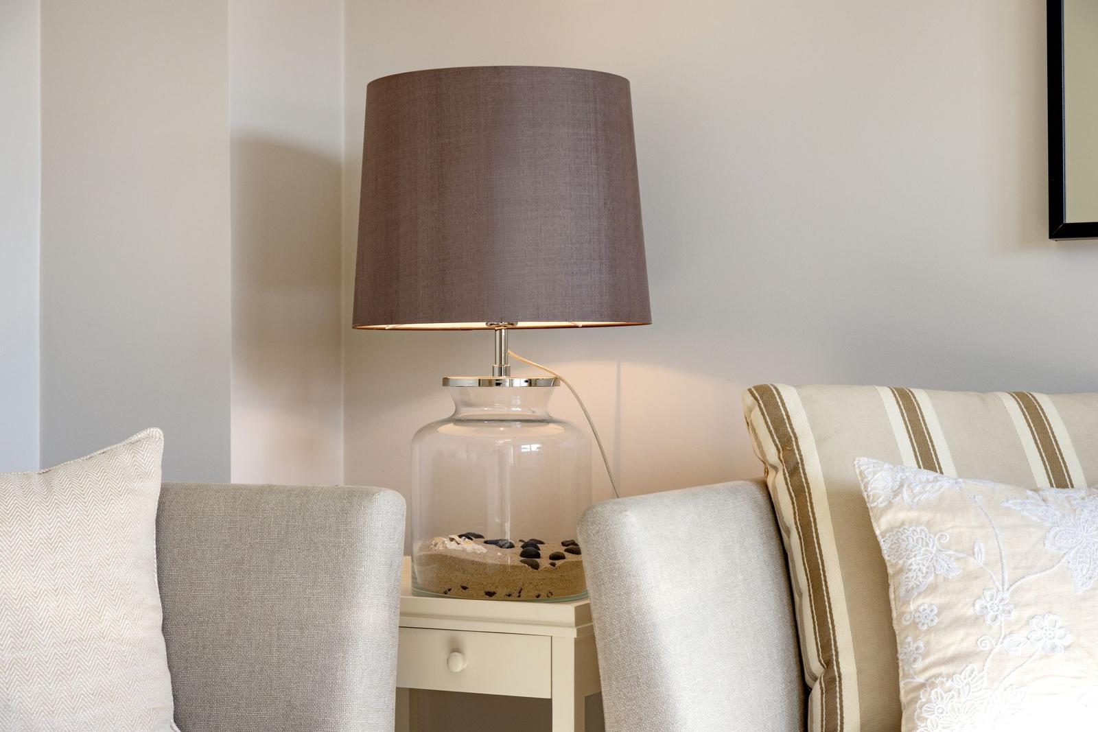 Tischlampe auf Nachttisch zwischen zwei Sofas mit Kissen.