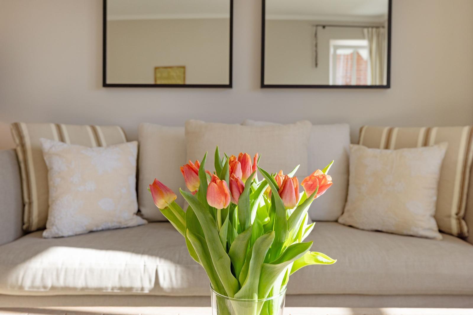 Ein Sofa mit Kissen und Tulpen im Vordergrund.