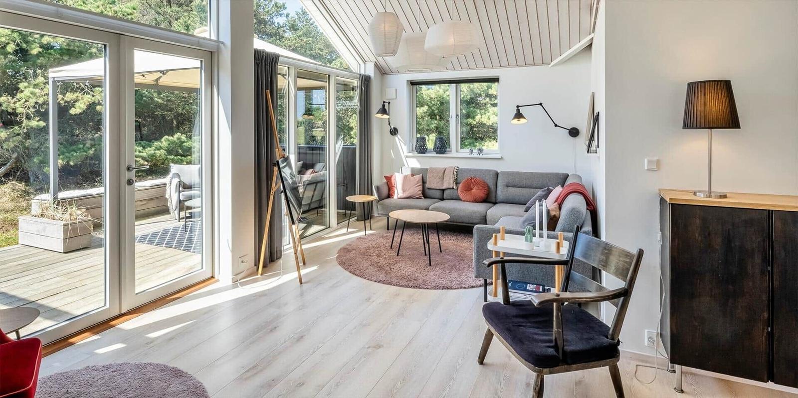 Wohnzimmer mit Sofa, Tischen und Blick auf die Terrasse.