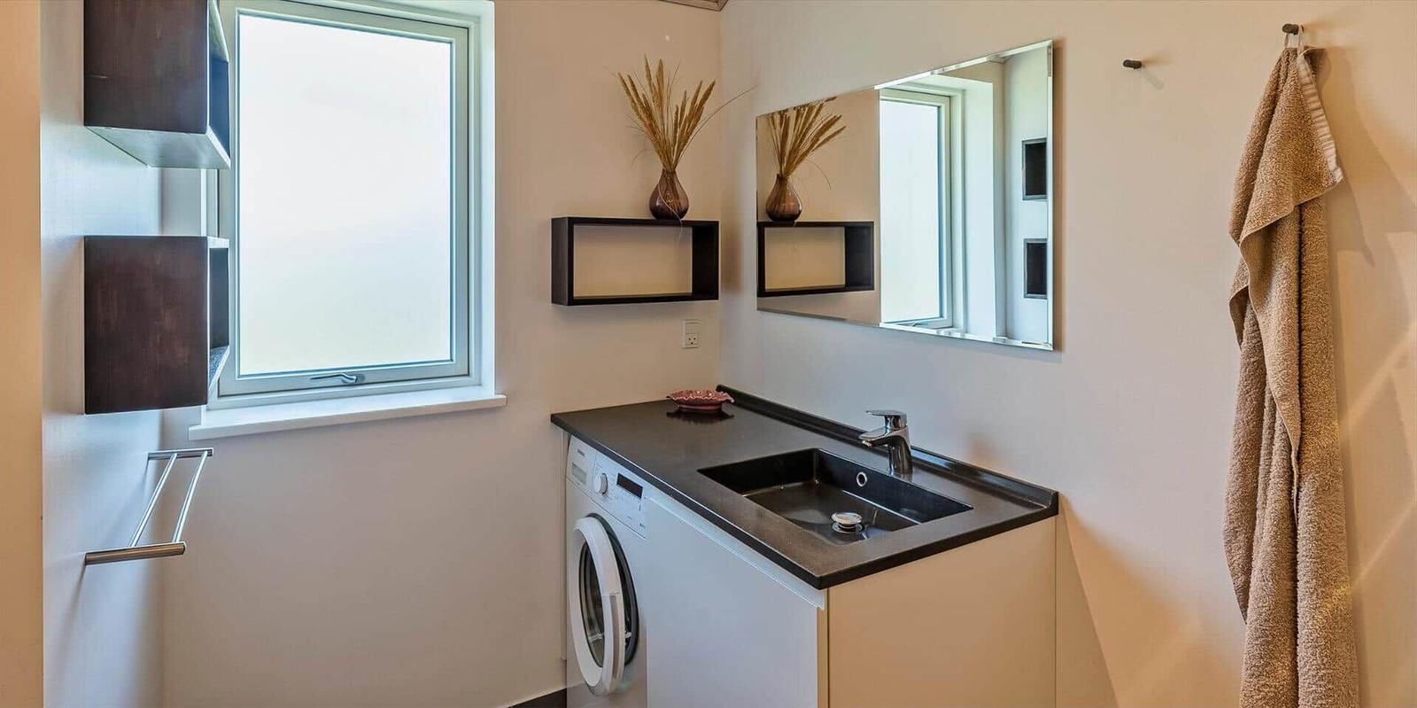 Badezimmer mit Waschmaschine, Spiegel und Fenster.